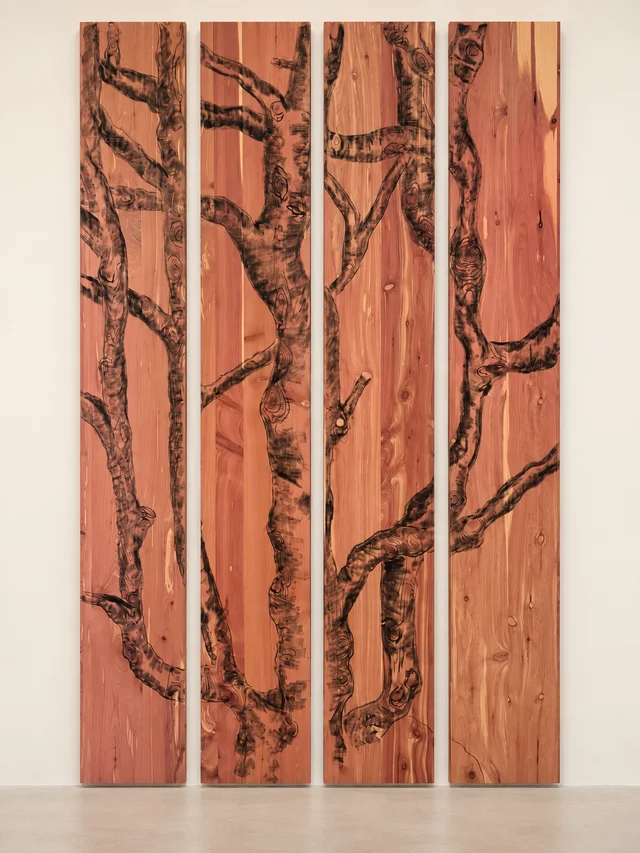 Four reddish wood panels with a continuous tree drawing in charcoal and pyrography